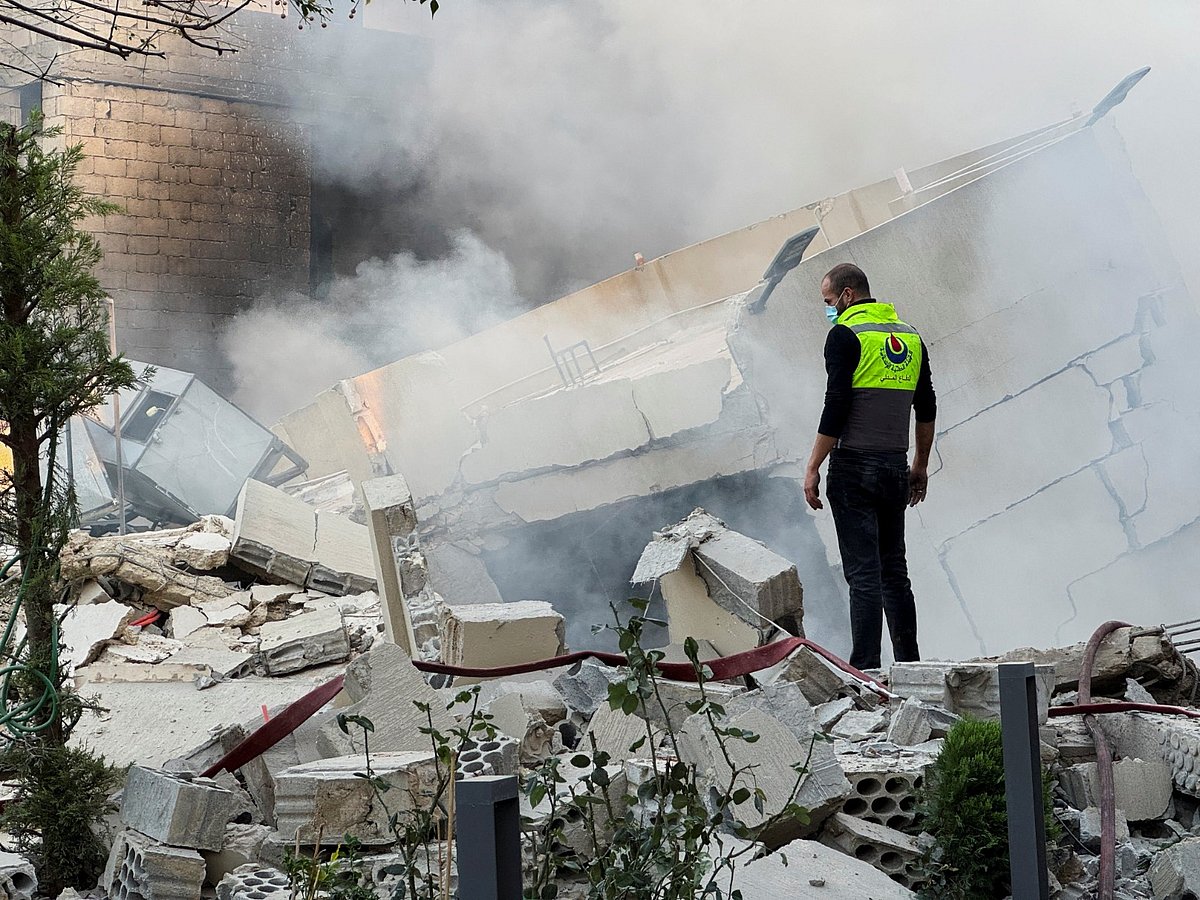 A civil defence member stands on rubble at a damaged site after Israeli military strike in Lebanon.