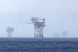 FILE - Oil platforms are visible through the haze near the Flower Garden Banks National Marine Sanctuary in the Gulf of Mexico, off the coast of Galveston, Texas, Saturday, Sept. 16, 2023. 