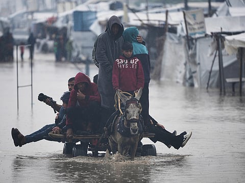 Palestinians cross a flooded street following heavy rain in Khan Younis, southern Gaza Strip, Thursday, Dec. 11, 2025. (AP Photo/Abdel Kareem Hana)