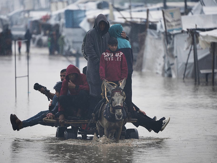 Palestinians cross a flooded street following heavy rain in Khan Younis, southern Gaza Strip, Thursday, Dec. 11, 2025. (AP Photo/Abdel Kareem Hana)