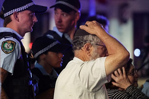 A member of the Jewish community reacts as he walks with police towards the scene of a shooting at Bondi Beach in Sydney.