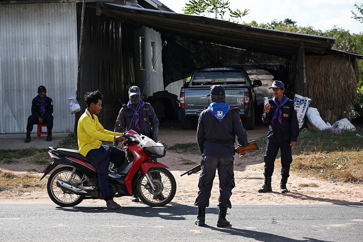 Security volunteers check the identification of a motorist as they remain in the evacuation zone to protect villagers' homes and livestock during the conflict in the Thai province of Buriram, ten kilometres away from the border with Cambodia on December 13, 2025.