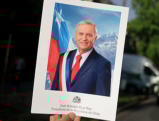 A person shows a sign depicting Chile's presidential candidate Jose Antonio Kast, of the Partido Republicano party, that reads his name and "President of the Republic of Chile", following the first results of the presidential runoff election in Santiago on December 14, 2025.