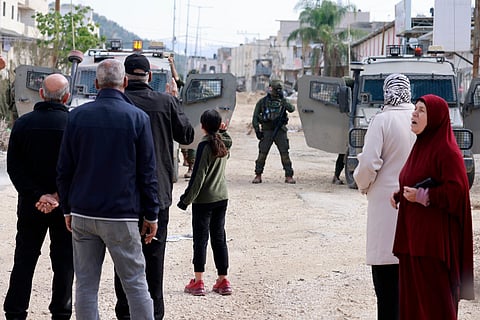 Palestinians rally as Israeli soldiers block the entrance of the Nur Shams Palestinian refugee camp, in the Israeli-occupied northern West Bank on December 15, 2025, as they demand to be allowed back to their homes after the Israeli army expelled them and others in early 2025.