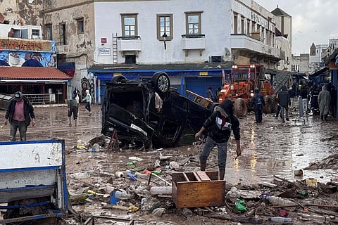 Moroccans looks at a destroyed vehicle and other debris following a flash flood, in the coastal town of Safi, some 300 kilometres south of the capital Rabat on December 15, 2025.