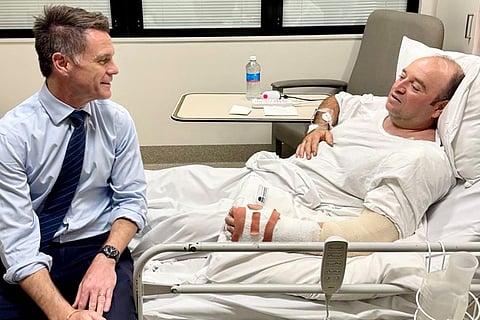 This handout photo taken and received from the NSW Premier's Department on December 15, 2025 shows New South Wales Premier Chris Minns (L) talking with Ahmed Al Ahmed, the man who tackled and disarmed one of the Bondi beach attackers, at St George Hospital in Sydney.