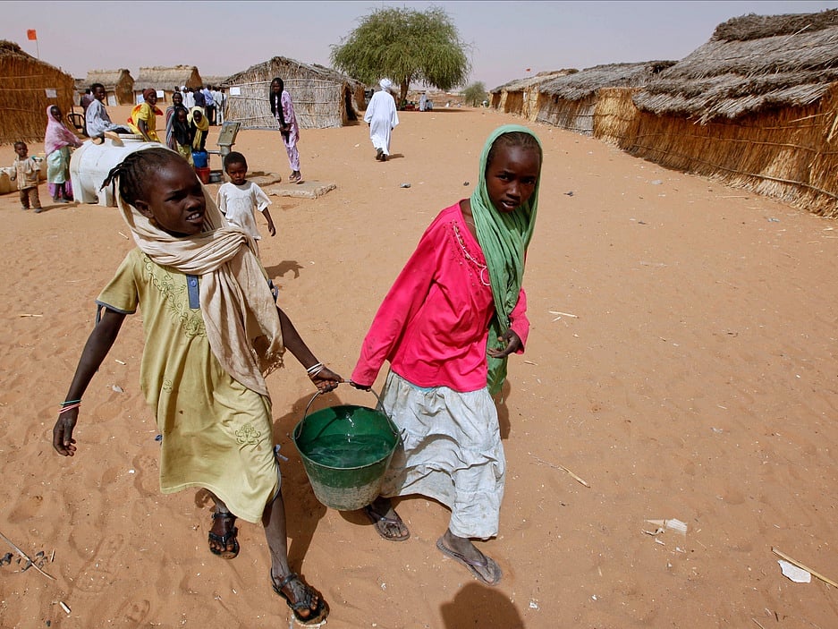 Sudanese refugee girls carry water supplies near a polling station in the refugee camp of Zamzam, on the outskirts of El Fasher, Darfur, Sudan 