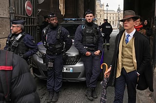 Pedro Elias Garzon Delvaux, right, walks past as police officers block an entrance to the Louvre after thieves carried out a daylight raid on French crown jewels, in Paris, Oct. 19, 2025.