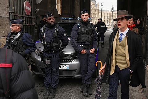 Pedro Elias Garzon Delvaux, right, walks past as police officers block an entrance to the Louvre after thieves carried out a daylight raid on French crown jewels, in Paris, Oct. 19, 2025.
