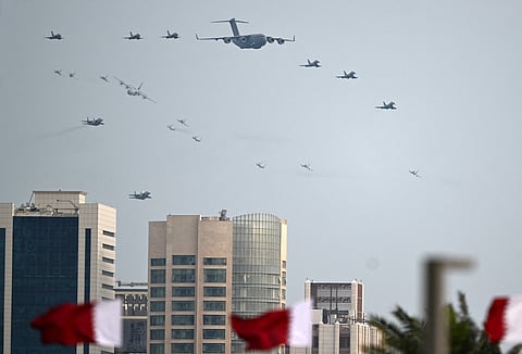 The national flags flutter as the Qatari Air Force takes part in a flypast during celebrations marking Qatar National Day, in Doha on December 18, 2025.