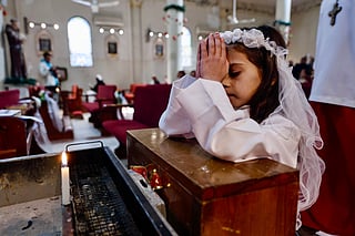 A young Christian worshipper prays during Christmas celebrations at the Holy Family Parish in Gaza City on December 21, 2025.
