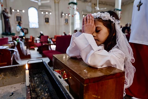 A young Christian worshipper prays during Christmas celebrations at the Holy Family Parish in Gaza City on December 21, 2025.