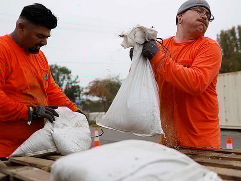 Los Angeles County workers load sandbags for a resident, near the Eaton Fire burn zone, in preparation for a strong atmospheric river storm arriving today to the region.