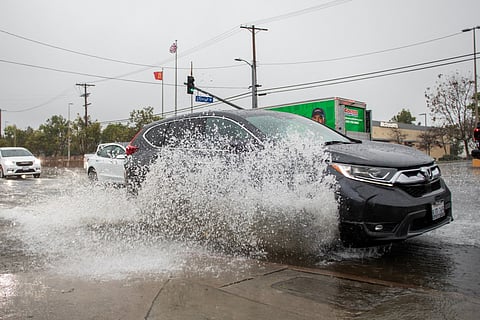 A car drives through a flooded road on La Cienega Boulevard on December 24, 2025 in Los Angeles, California.