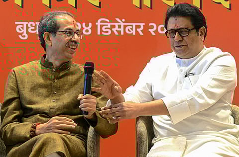 Uddhav Thackeray (L), President of Shiv Sena (UBT), and his cousin Raj Thackeray, Chief of Maharashtra Navnirman Sena (MNS), react while addressing a joint presser announcing a formal alliance in Mumbai on December 24, 2025, ahead of the upcoming local body elections.