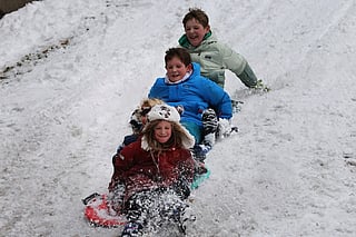 Children sled in the snow in Brooklyn after an overnight storm on December 27, 2025 in New York City.