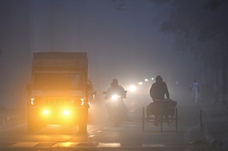 Commuters ride along a road amid dense smog on a cold winter morning in New Delhi on December 31, 2025.