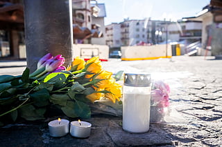 Flowers and candles laid on the ground near the bar Le Constellation following a fire that ripped through the venue in Crans-Montana, during New Year's Eve celebrations.
