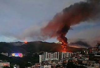 Fire at Fuerte Tiuna, Venezuela's largest military complex, is seen from a distance after a series of explosions in Caracas on January 3, 2026.