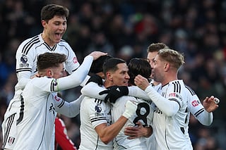 Fulham's Welsh midfielder #08 Harry Wilson (C) is mobbed by teammates after scoring the opening goal to take the lead 1-0 during the English Premier League football match between Fulham and Liverpool at Craven Cottage in London on January 4, 2026.