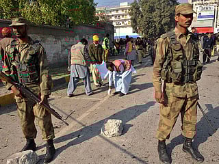 Pakistani army soldiers stand guard at a suicide blast site in Peshawar on December 24, 2009. 