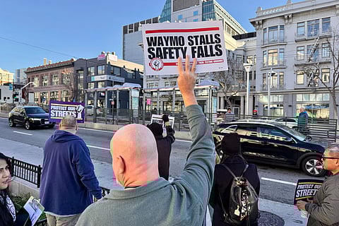 Demonstrators holds signs during a protest by Uber and Lyft drivers asking state regulators to take self-driving taxis off the streets due to safety concerns at the California Public Utilities Commission headquarters Friday, Jan. 9, 2026, in San Francisco. (AP Photo/Haven Daley)