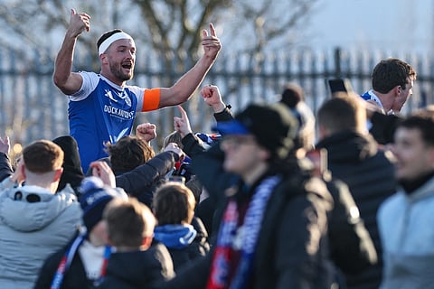 Macclesfield's English midfielder #06 Paul Dawson (top L) is hoisted above the crowd as supporters storm the pitch to celebrate the team's victory at the end of the English FA Cup third round football match between Macclesfield Town and Crystal Palace at Leasing.com Stadium, Moss Rose in Macclesfield, northern England on January 10, 2026.
