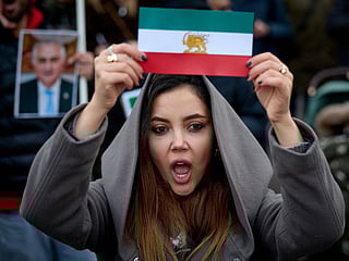 A protester shows an Iran's pre-1979 Islamic Revolution flag during a demonstration to support mass rallies denouncing the Islamic republic in Iran in Paris on January 11, 2026.  