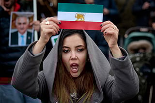 A protester shows an Iran's pre-1979 Islamic Revolution flag during a demonstration to support mass rallies denouncing the Islamic republic in Iran in Paris on January 11, 2026.  