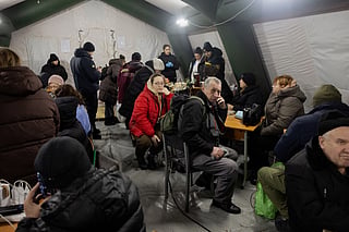 People charge their devices under a tent at Kyiv’s “Point of Invincibility” on January 11, 2026—a warming and charging station set up after Russian missile and drone strikes hit Ukraine’s energy infrastructure during the ongoing invasion.