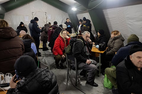 People charge their devices under a tent at Kyiv’s “Point of Invincibility” on January 11, 2026—a warming and charging station set up after Russian missile and drone strikes hit Ukraine’s energy infrastructure during the ongoing invasion.
