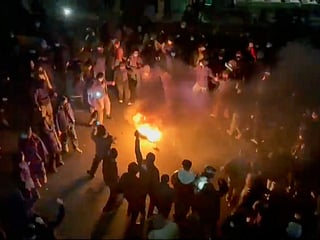 In this frame grab from footage circulating on social media shows protesters dancing and cheering around a bonfire as they take to the streets in Tehran, Iran. 