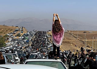 This UGC image posted on Twitter reportedly on October 26, 2022 shows an unveiled woman standing on top of a vehicle as thousands make their way towards Aichi cemetery in Saqez, Mahsa Amini's home town in the western Iranian province of Kurdistan, to mark 40 days since her death, defying heightened security measures as part of a bloody crackdown on women-led protests.  