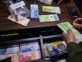 A currency exchange employee counts newly issued Syrian pound banknotes in Damascus, Syria, Saturday, January 3, 2026. 