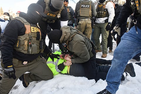 ICE and other federal officers detain a person during protests as ICE operates in a residential neighborhood in Minneapolis, Minnesota, on January 13, 2026.