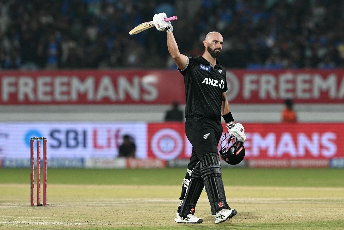 New Zealand's Daryl Mitchell celebrates after scoring a century (100 runs) during the second one-day international (ODI) cricket match between India and New Zealand at Niranjan Shah Stadium in Rajkot on January 14, 2026.