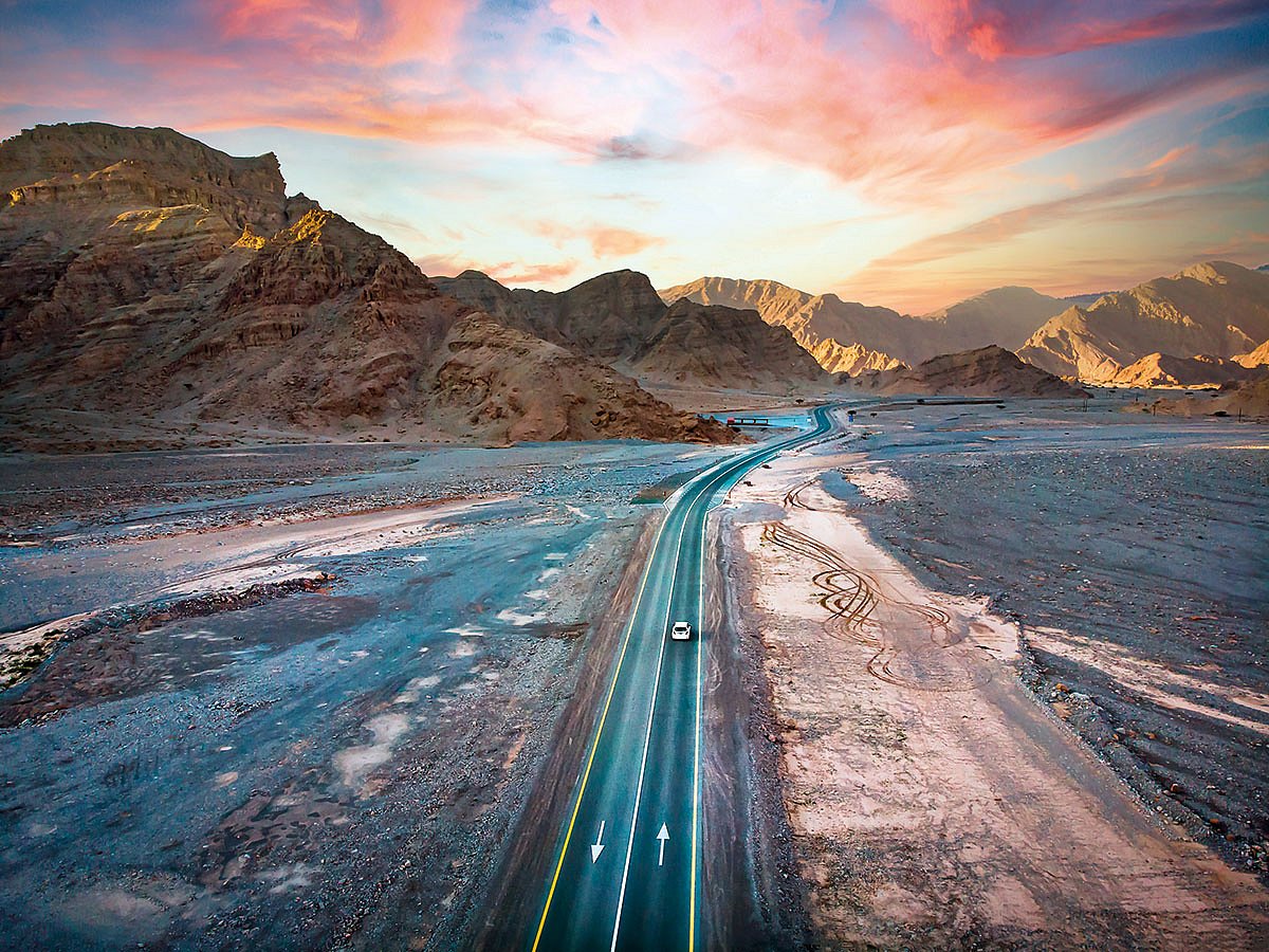 Jebel Jais mountain desert road surrounded by sandstones in Ras Al Khaimah. This is the season when a drive becomes more than a commute, when mountains, desert edges and coastlines start to feel cinematic and inviting.