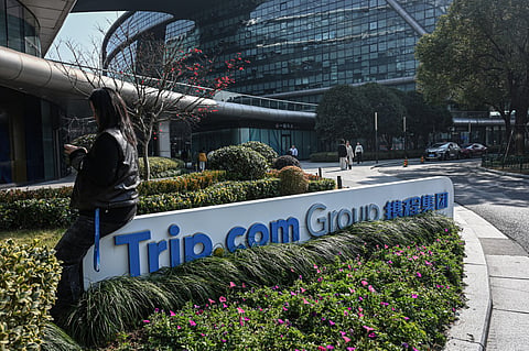A woman sits on a signage of China's travel agency Trip.com Group at its headquarter in Shanghai.
