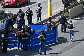 Police officers stand guard as Public Ministry prosecutors collect evidence at the crime scene where a police officer was killed by alleged gang members in Guatemala City on January 18, 2025.