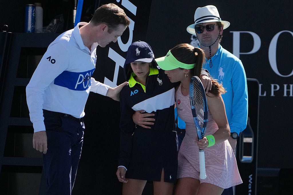 Zeynep Sonmez of Turkey and umpire Chase Urban help a ball kid who fainted, from the court during her first round match against Ekaterina Alexandrova of Russia at the Australian Open tennis championship in Melbourne, Australia, Sunday, Jan. 18, 2026.