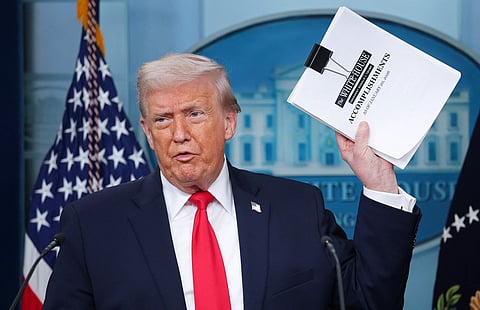 President Donald Trump displays a stack of papers labeled "The White House Accomplishments" as he arrives for a press briefing in the James S. Brady Press Briefing Room of the White House on January 20, 2026 in Washington, DC. 