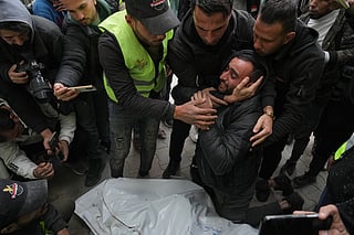 People mourn over the bodies of the Palestinian journalists Abd Shaat and Mohamed Qeshta, who were killed in an Israeli strike on a vehicle, before their funeral at Shifa Hospital, in Gaza City, Wednesday, Jan. 21, 2026.
