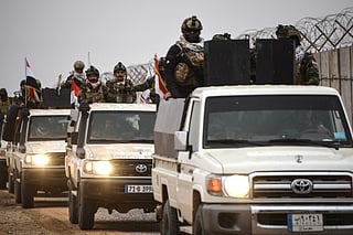 Members of Iraq’s Popular Mobilization Forces drive along the Syrian border in northwestern Iraq in January.