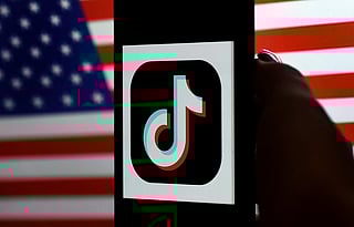 Photo illustration shows the TikTok logo displayed on the screen of an iPhone on a US flag background.