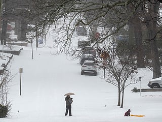 A parent and kid play in the snow on Palm street on January 24, 2026 in Little Rock, Arkansas. A massive winter storm is bringing frigid temperatures, ice, and snow to nearly 200 million Americans.  