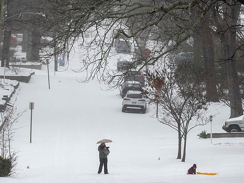 A parent and kid play in the snow on Palm street on January 24, 2026 in Little Rock, Arkansas. A massive winter storm is bringing frigid temperatures, ice, and snow to nearly 200 million Americans.  