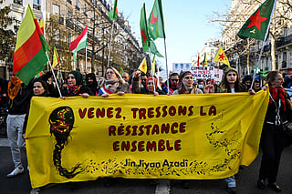 Protesters hold a banner reading "Come and weave resistance together" and "Women, life, freedom", the slogan is a popular political Kurdish slogan that became a rallying cry during the protests which occurred in Iran as a response to the death of Mahsa Amini, while taking part in a demonstration in solidarity with Kurds in northern Syria, in central Paris, on January 24, 2026.