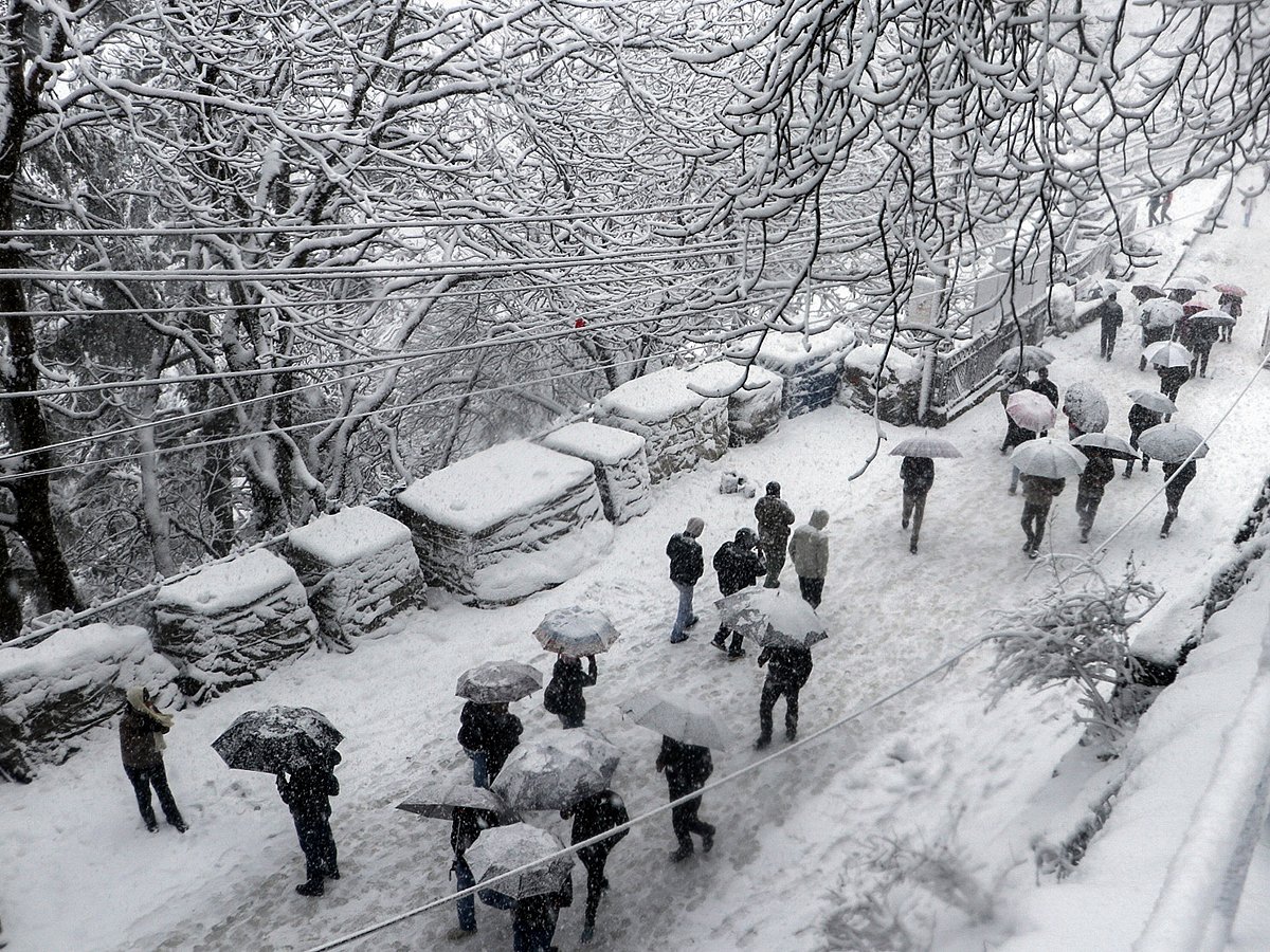 Commuters walk on a snow-covered road as the city receives a heavy snowfall, in Shimla.