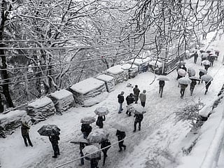 Commuters walk on a snow-covered road as the city receives a heavy snowfall, in Shimla.