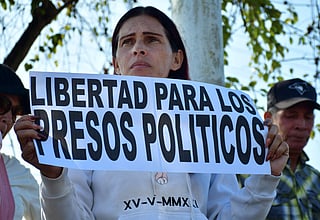 A woman shows a sign that reads "Freedom for political prisoners" during a demonstration to demand the freedom of Venezuelan political prisoners in front of Tocuyito prison in Tocuyito, near Valencia, Venezuela on January 20, 2026.